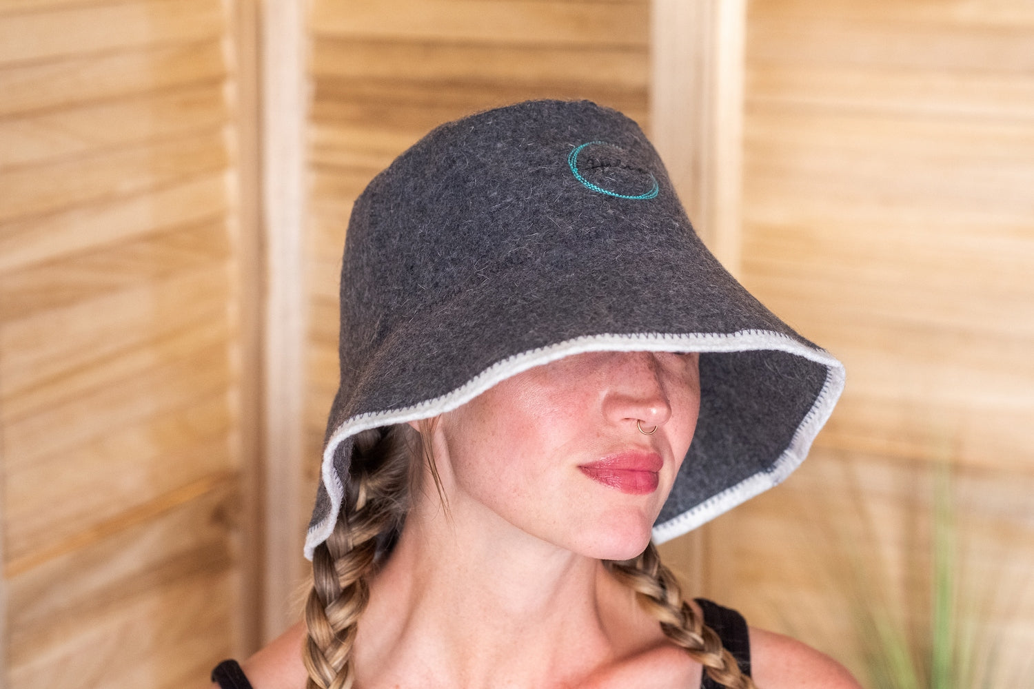 Woman wearing Halsa Bucket Wool Sauna Hat in a wood-paneled sauna